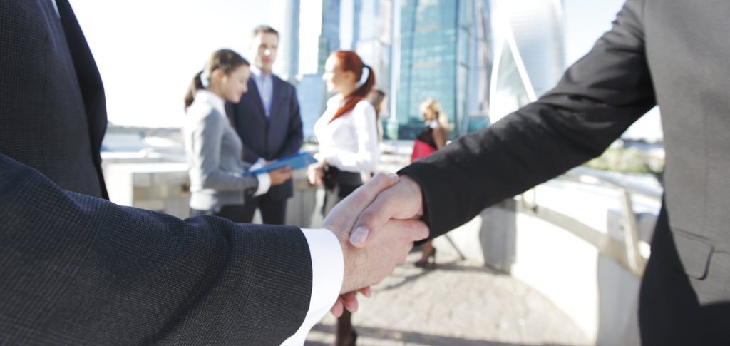 Business handshake, the deal Is finalized by group of people outside